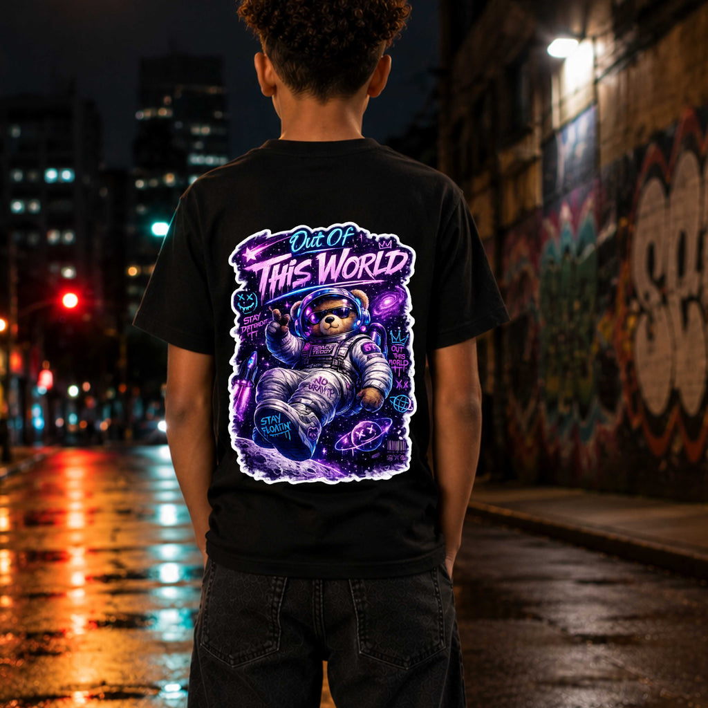 Person wearing a black t-shirt with a colorful graphic design on the back, standing on a city street at night.