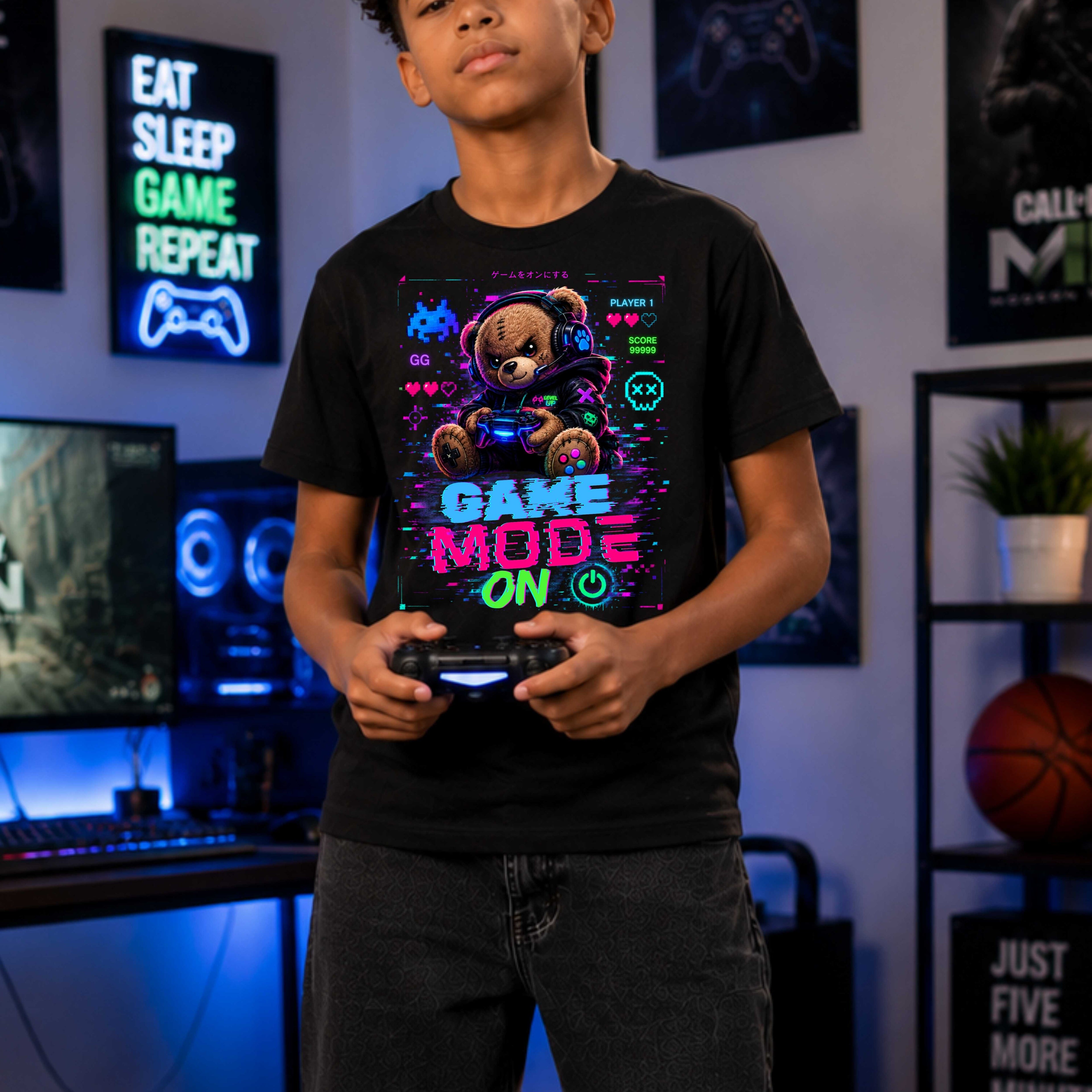 Person wearing a black t-shirt with a colorful graphic and text, holding a gaming controller in a room with gaming decor.