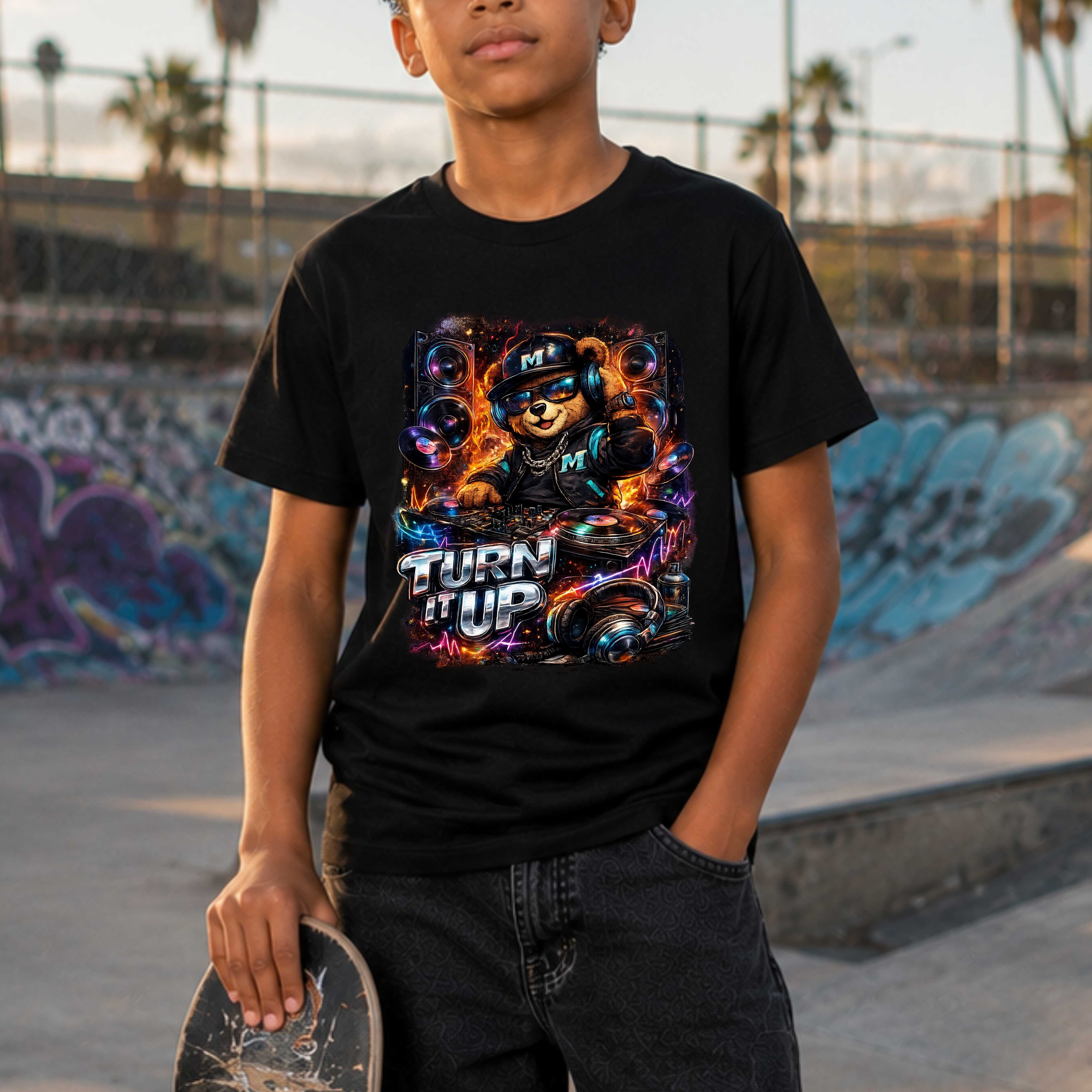 Person wearing a black t-shirt with a colorful graphic and text, holding a skateboard in a skate park.