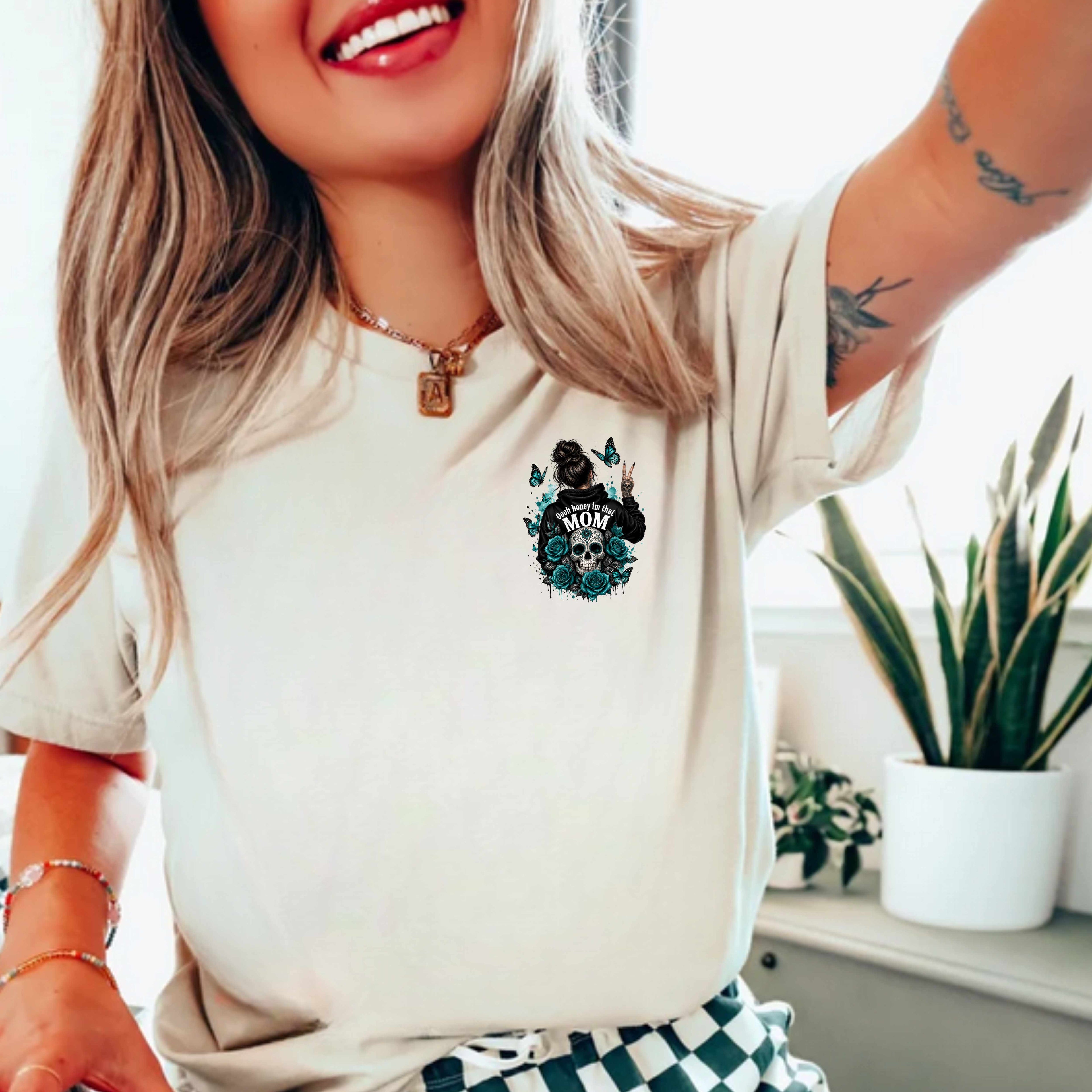 Woman wearing a Natural t-shirt with a graphic design, standing indoors with plants in the background.