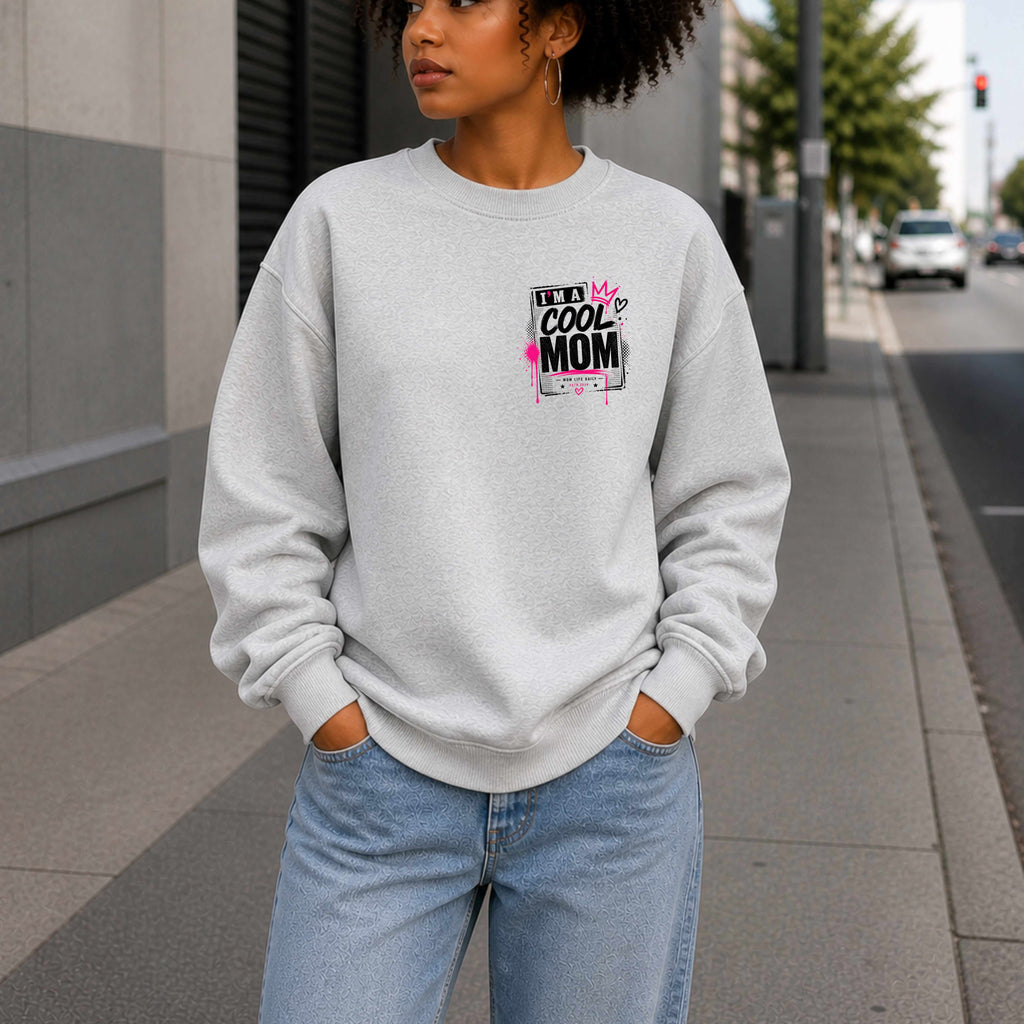 Person wearing a gray sweatshirt with a graphic design Say's I'm A  Cool Mom on a city street.