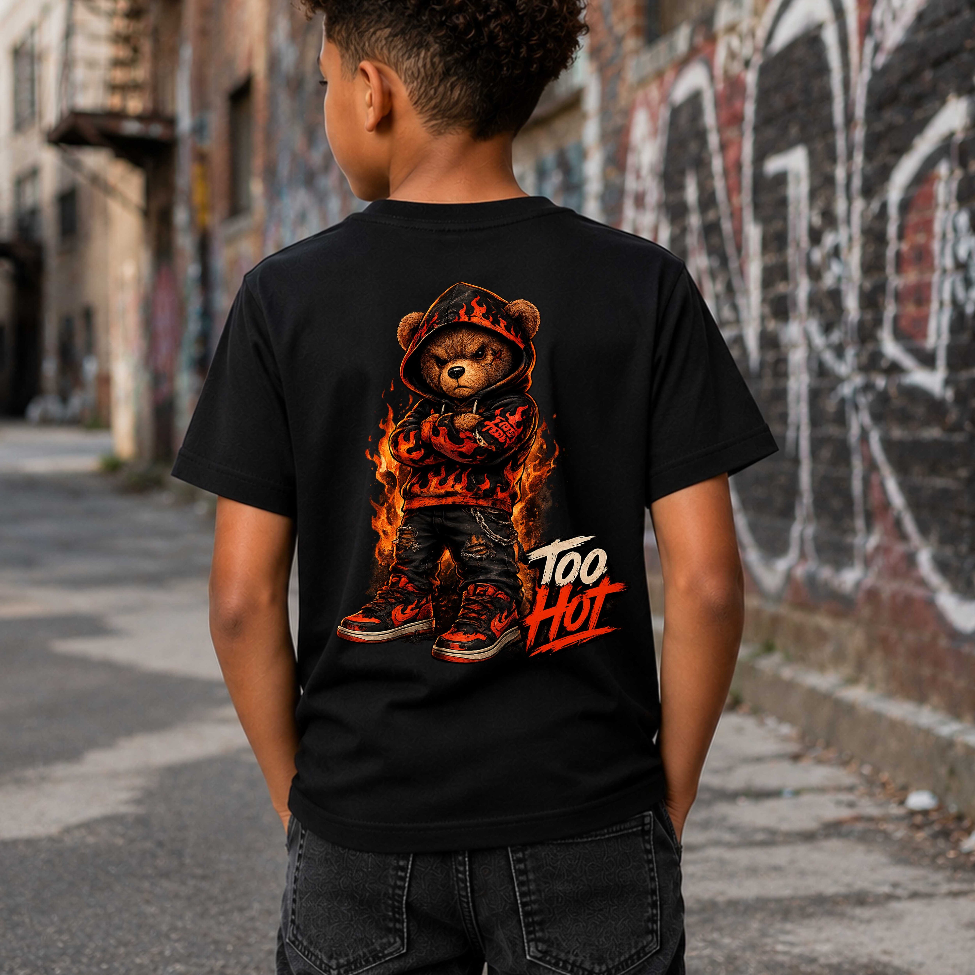 Child wearing a black t-shirt with a bear graphic and 'Too Hot' text, standing in an alleyway.
